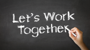 Hand writing "Let's Work Together" on a chalkboard